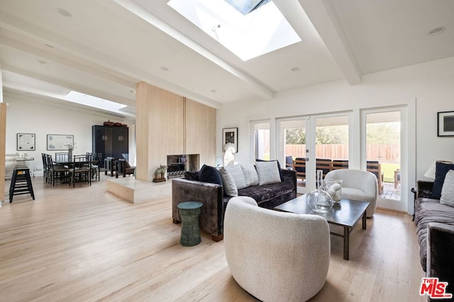 living room featuring light hardwood / wood-style flooring, lofted ceiling with skylight, and french doors