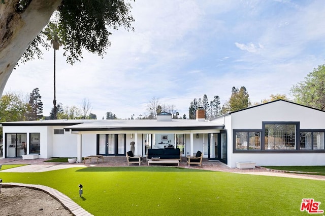 rear view of property with an outdoor living space, a patio, and a lawn