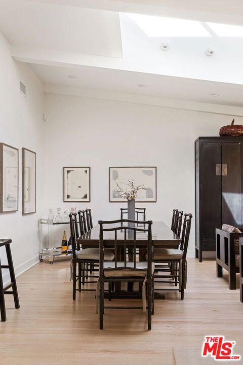 dining area featuring lofted ceiling with beams and light wood-type flooring