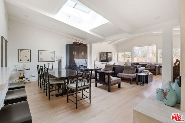 dining room featuring light hardwood / wood-style floors and vaulted ceiling with skylight