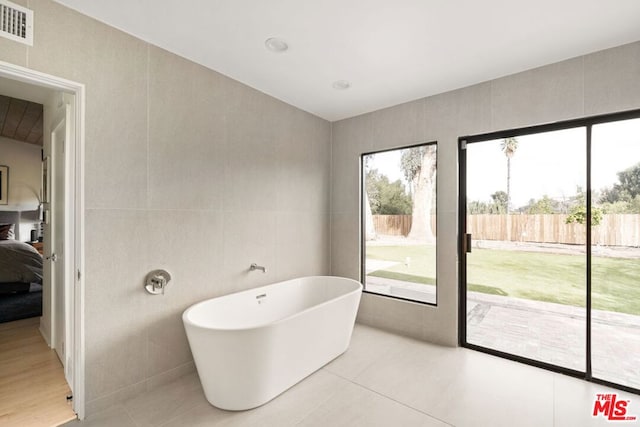 bathroom with a bathing tub and tile walls