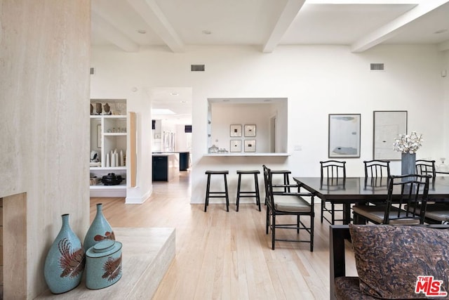 dining room featuring beam ceiling and light hardwood / wood-style flooring