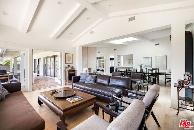 living room featuring lofted ceiling with beams and light wood-type flooring