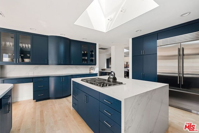 kitchen featuring blue cabinets, light hardwood / wood-style floors, appliances with stainless steel finishes, and a kitchen island