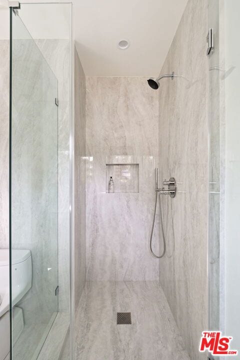 bathroom featuring a tile shower and toilet