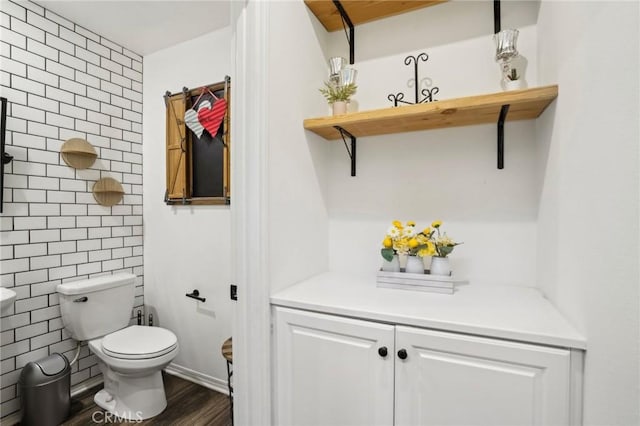 half bath featuring toilet, tile walls, and wood finished floors