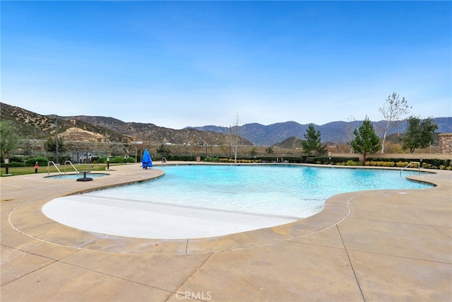 community pool with a community hot tub, a patio area, and a mountain view