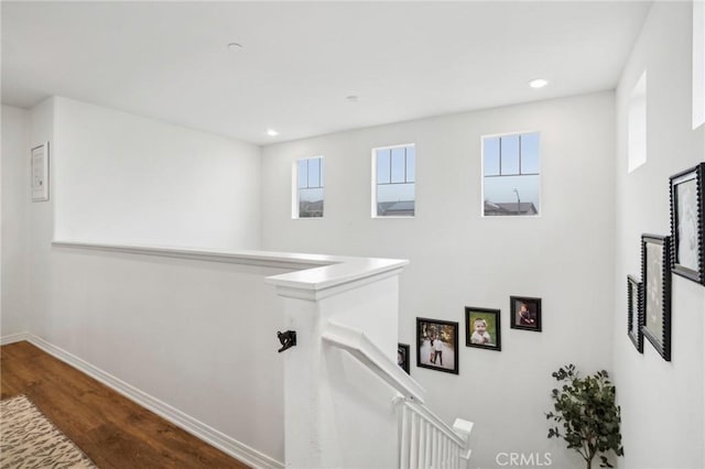 hall featuring recessed lighting, baseboards, wood finished floors, and an upstairs landing