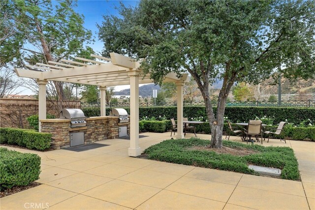 view of patio with exterior kitchen, grilling area, and fence