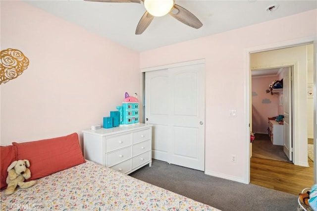 bedroom with a ceiling fan, baseboards, dark colored carpet, and a closet