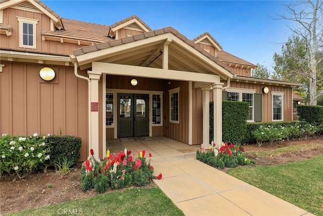 doorway to property with a tiled roof and board and batten siding