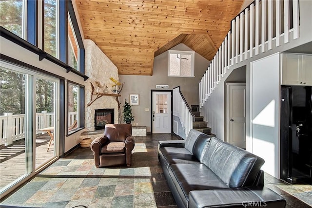 living room featuring stone tile floors, stairway, a stone fireplace, high vaulted ceiling, and wooden ceiling