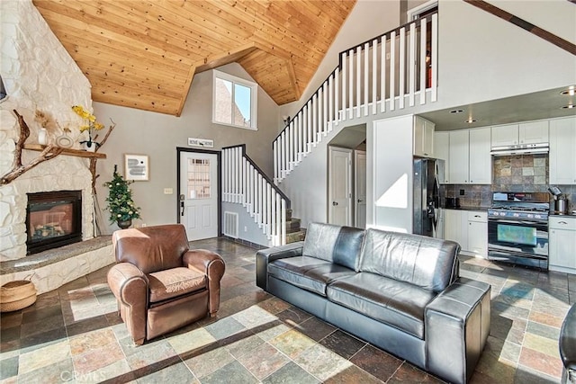 living area featuring high vaulted ceiling, a fireplace, wood ceiling, stairway, and stone tile flooring