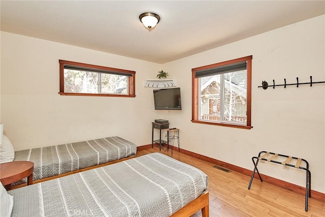 bedroom with multiple windows, wood-type flooring, visible vents, and baseboards