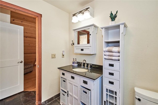 half bathroom featuring toilet, baseboards, and vanity