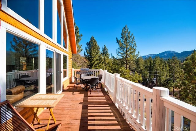 wooden terrace featuring outdoor dining space and a mountain view