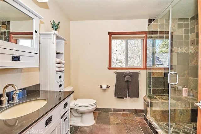 bathroom featuring a stall shower, stone tile flooring, vanity, and toilet