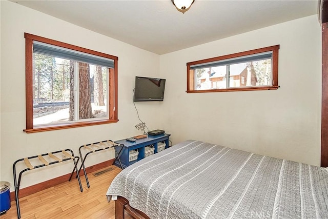 bedroom featuring light wood-type flooring, visible vents, and baseboards