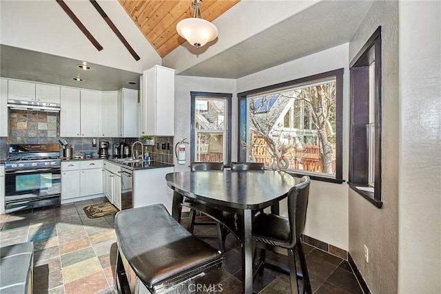 kitchen with dark countertops, white cabinetry, pendant lighting, a sink, and gas stove