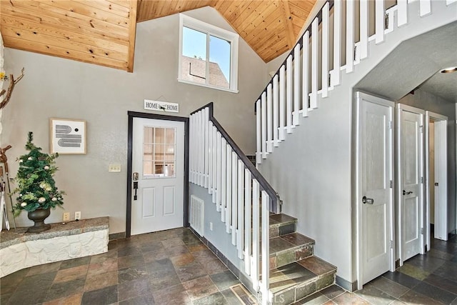 entryway with stairway, wood ceiling, stone finish floor, and baseboards