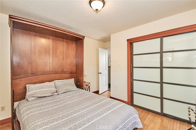 bedroom featuring light wood finished floors, a closet, and baseboards