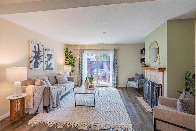 living room with a tiled fireplace and dark hardwood / wood-style floors