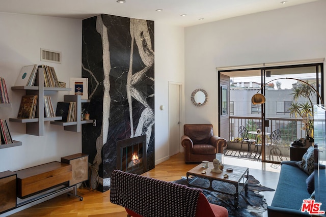 living room featuring a high end fireplace and light hardwood / wood-style flooring