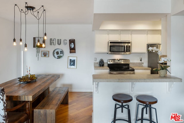 kitchen featuring white cabinetry, stainless steel appliances, kitchen peninsula, and light hardwood / wood-style flooring