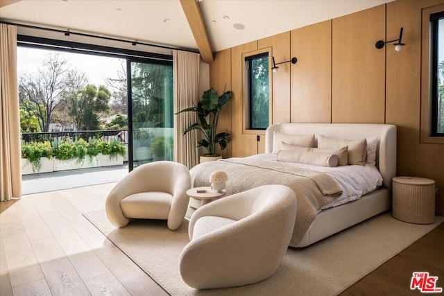 bedroom with multiple windows, beam ceiling, access to outside, and light wood-type flooring