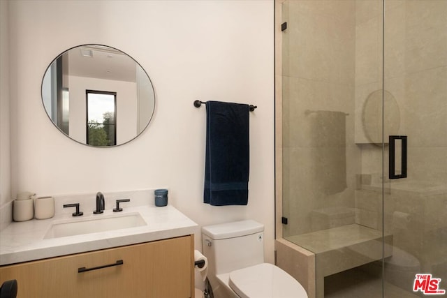 bathroom featuring a shower with door, vanity, and toilet