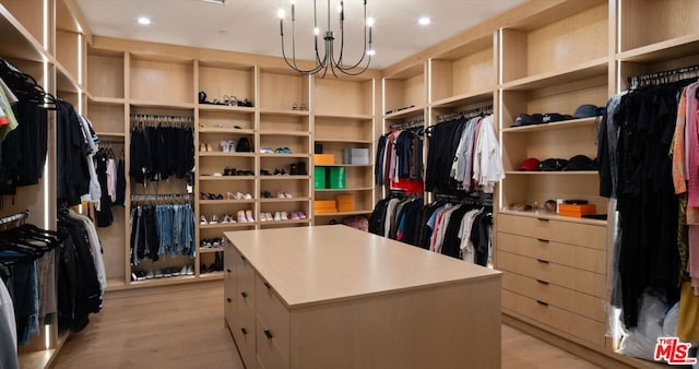 walk in closet with light hardwood / wood-style floors and a notable chandelier