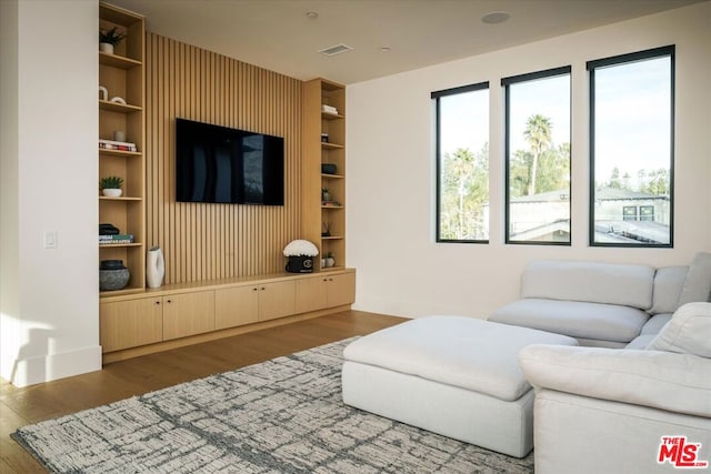 living room featuring wood-type flooring and built in features