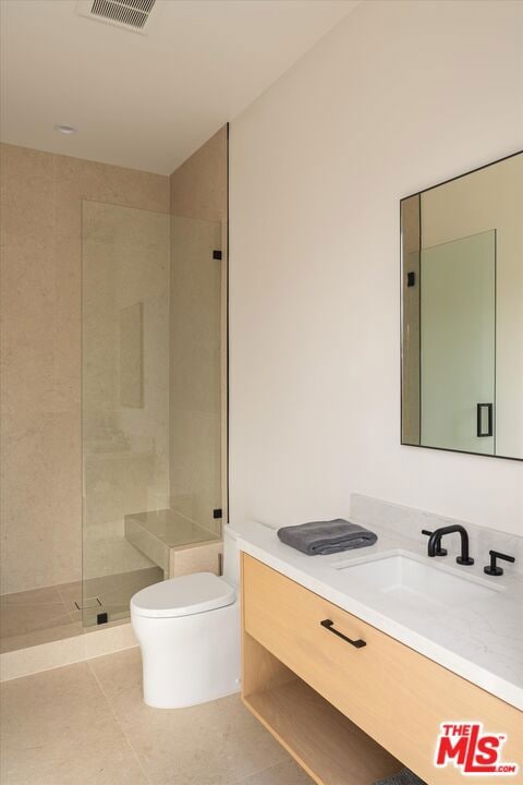 bathroom featuring vanity, tile patterned floors, toilet, and tiled shower