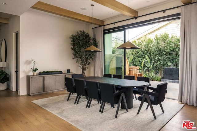 dining room featuring beamed ceiling, plenty of natural light, and light hardwood / wood-style flooring