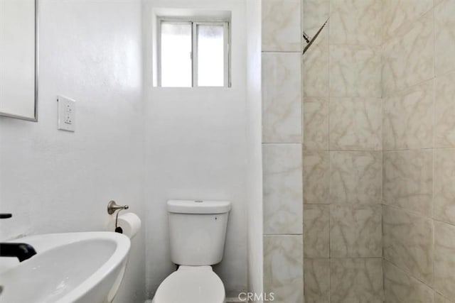 bathroom featuring tiled shower and toilet