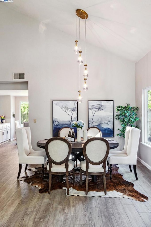 dining space with hardwood / wood-style floors and high vaulted ceiling