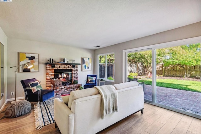 living room featuring a brick fireplace, hardwood / wood-style floors, and a textured ceiling