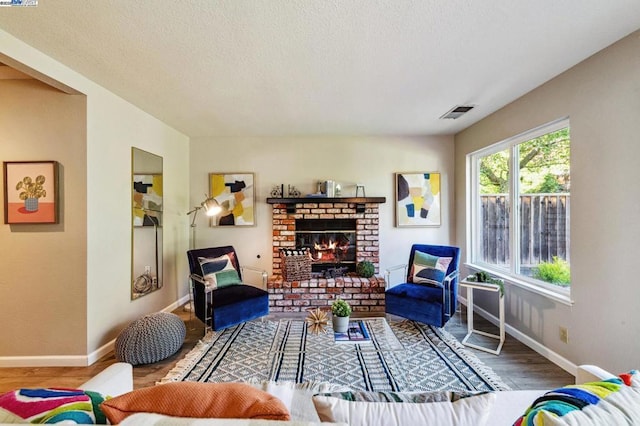 living room with hardwood / wood-style floors, a textured ceiling, and a fireplace