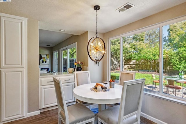 dining area with a healthy amount of sunlight, a notable chandelier, and dark hardwood / wood-style flooring