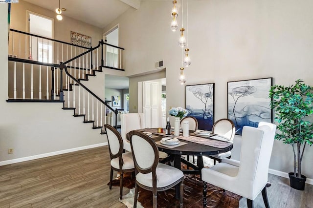 dining space featuring plenty of natural light, a towering ceiling, and dark hardwood / wood-style flooring