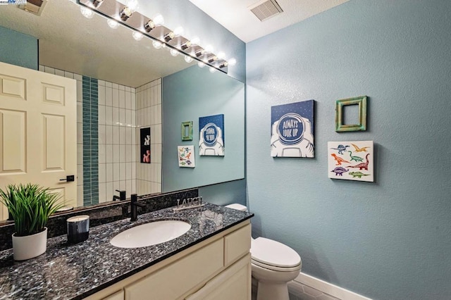 bathroom featuring tile patterned flooring, vanity, a shower, and toilet