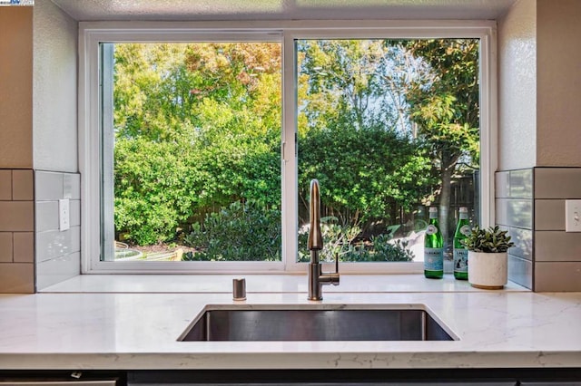 kitchen with light stone counters, sink, and a textured ceiling