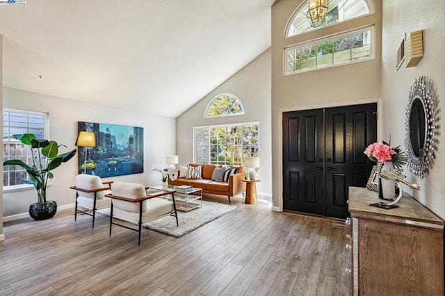 foyer entrance with high vaulted ceiling and light wood-type flooring