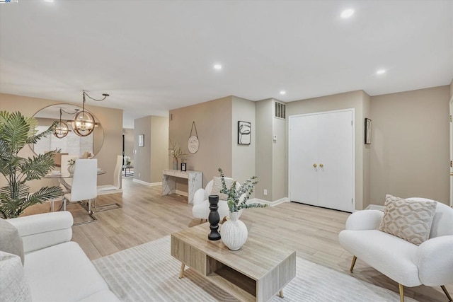 living room with a notable chandelier and light hardwood / wood-style flooring