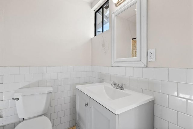 bathroom with vanity, toilet, and tile walls