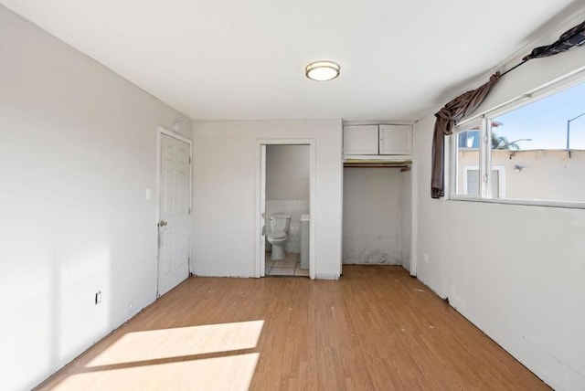 unfurnished bedroom featuring connected bathroom and light hardwood / wood-style flooring