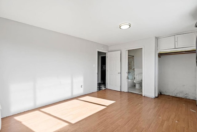 unfurnished bedroom featuring connected bathroom, light hardwood / wood-style floors, and a closet