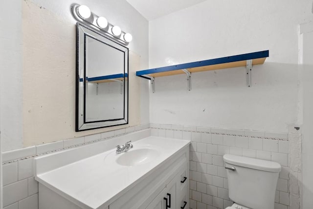 bathroom featuring vanity, tile walls, and toilet