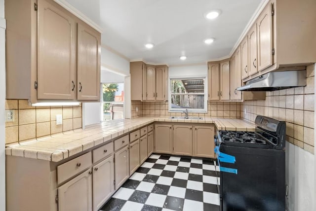 kitchen with black gas range, sink, tile countertops, and light brown cabinetry