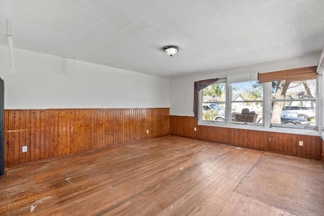 unfurnished room with wood-type flooring and wooden walls